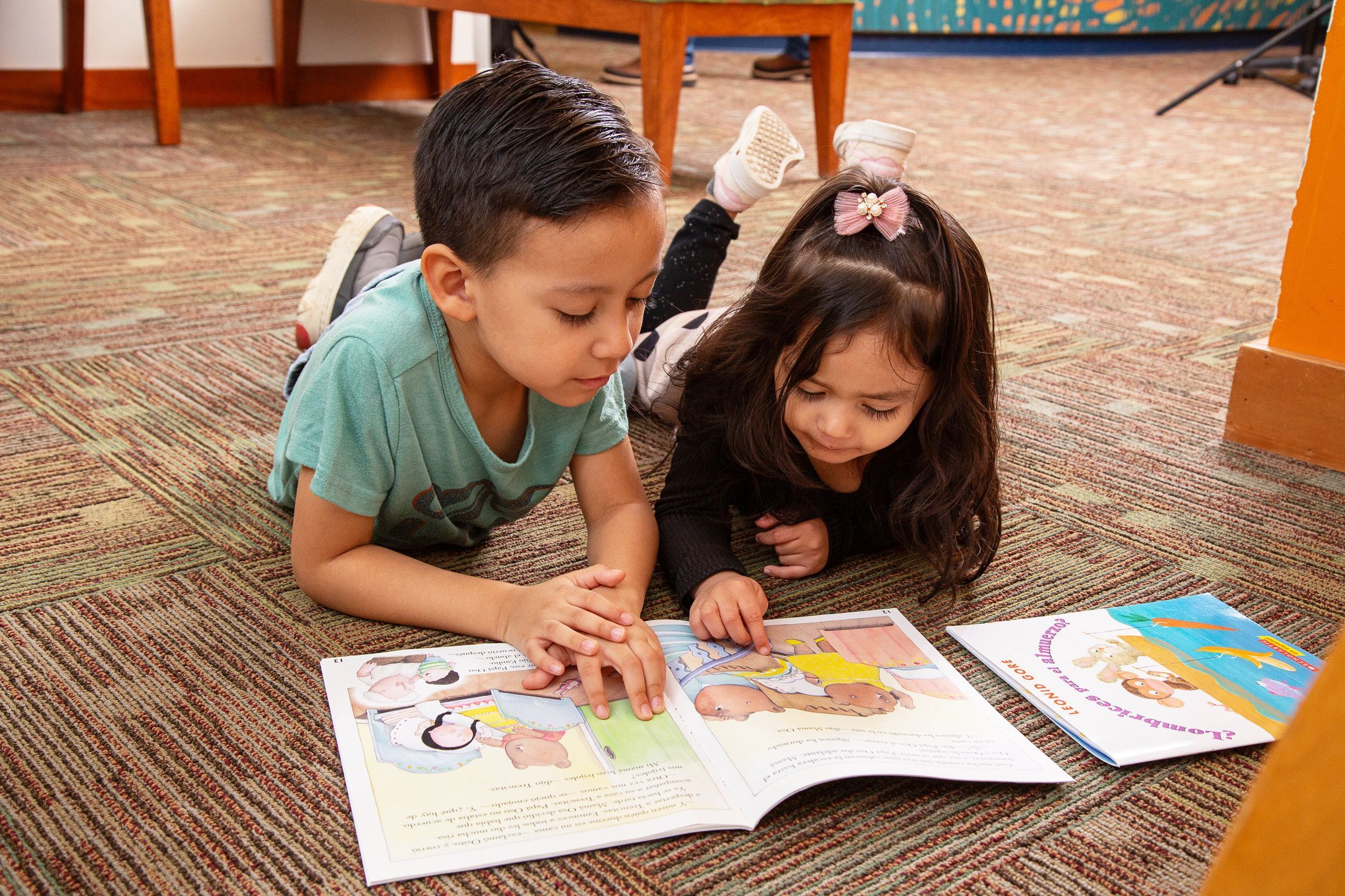 Boy and girl read picture book on floor together