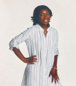 African American young woman posing with one hand on hip and smiling.
