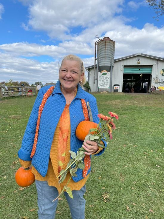 A grandmother poses with pumpkins and flowers picked at Snipes Farm Fall Festival