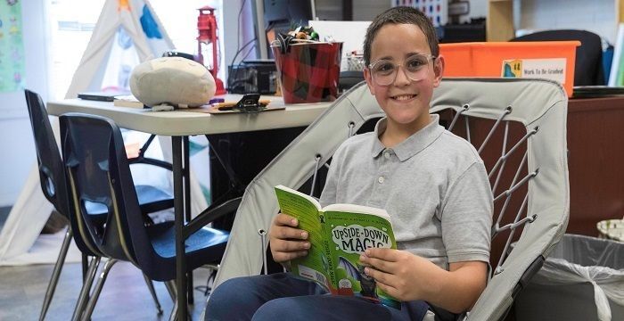 Student smiling and reading a book