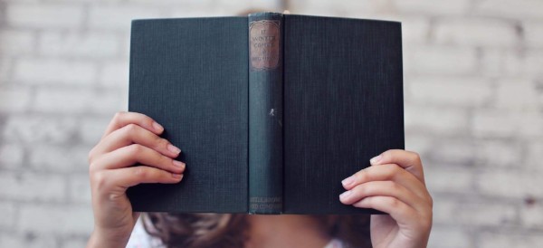 Person holding a book in front of her face