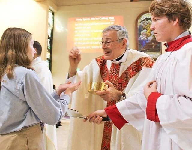 Bishop Gerald M. Barbarito distributes Communion during the Catholic Schools Week Mass for John Carroll High School at St. Anastasia in Fort Pierce.