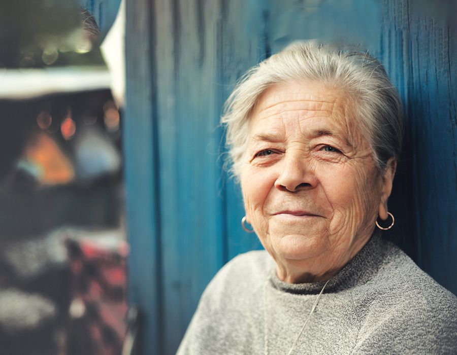 Older woman standing outside and smiling gently