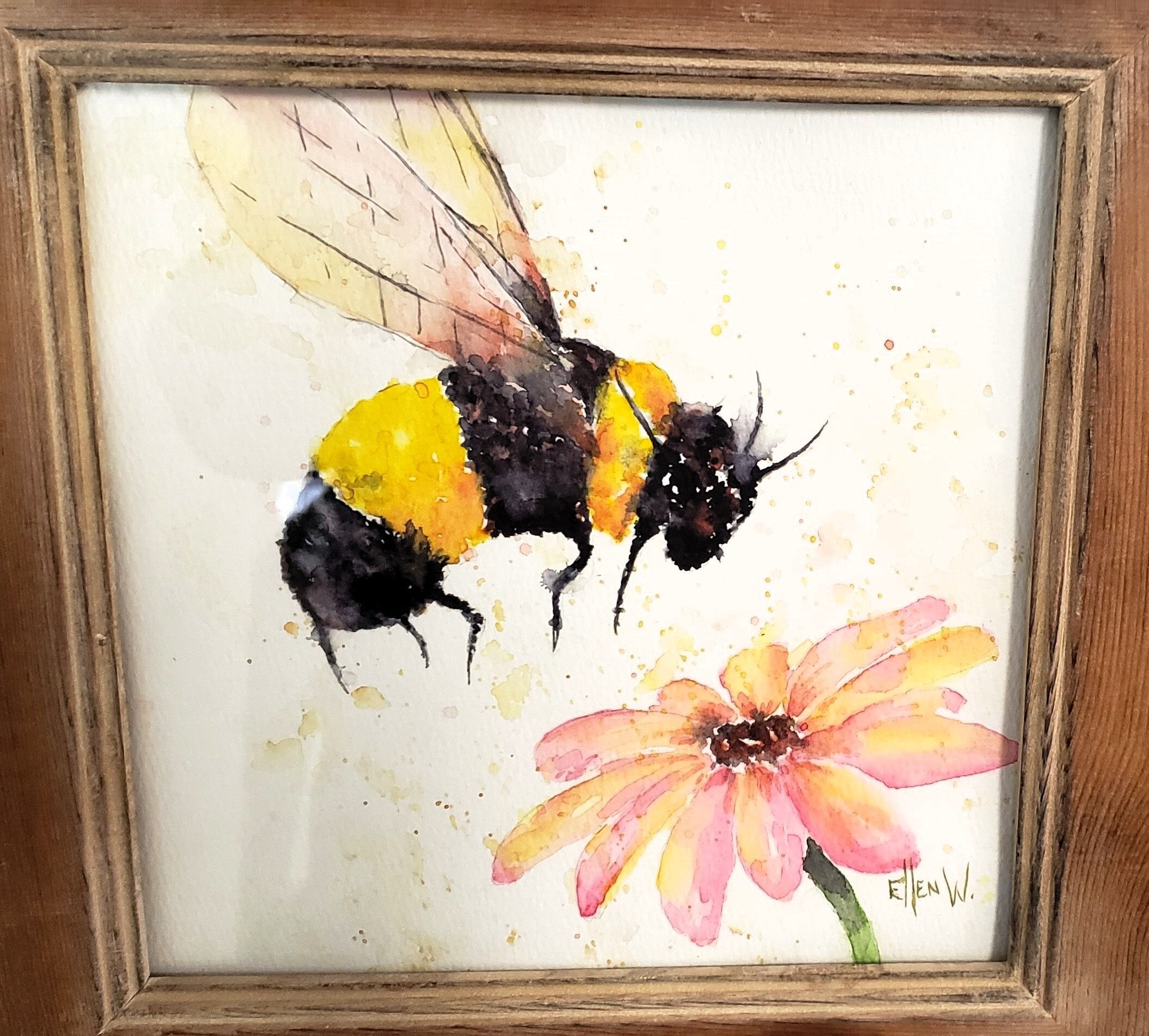 A yellow and black striped bee hovers over a pink flower with a dark center.