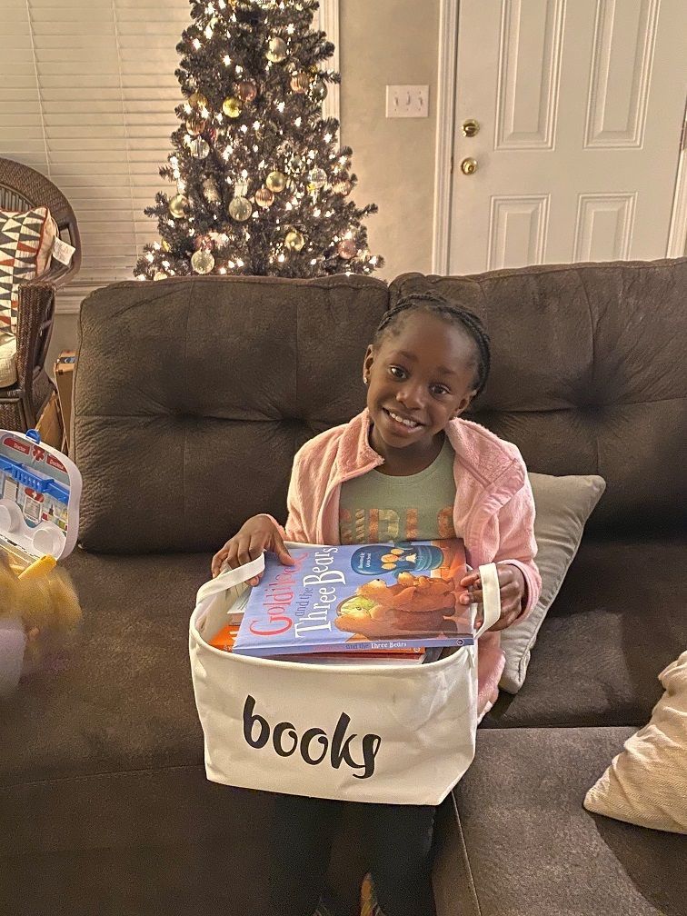 A child holds a basket of donated books. 