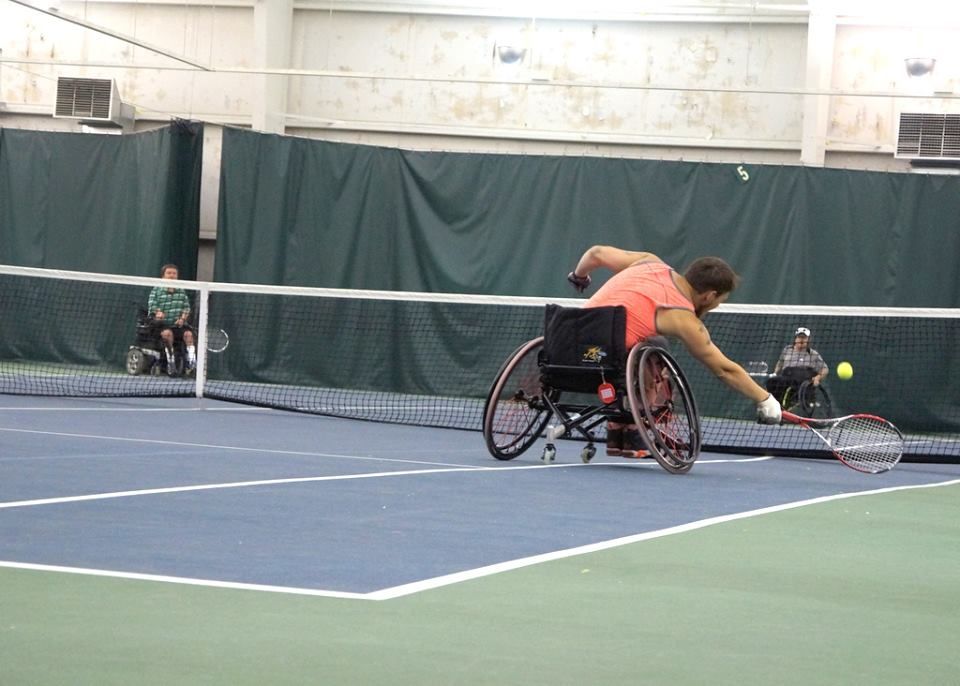 Adults in wheelchairs playing indoor tennis