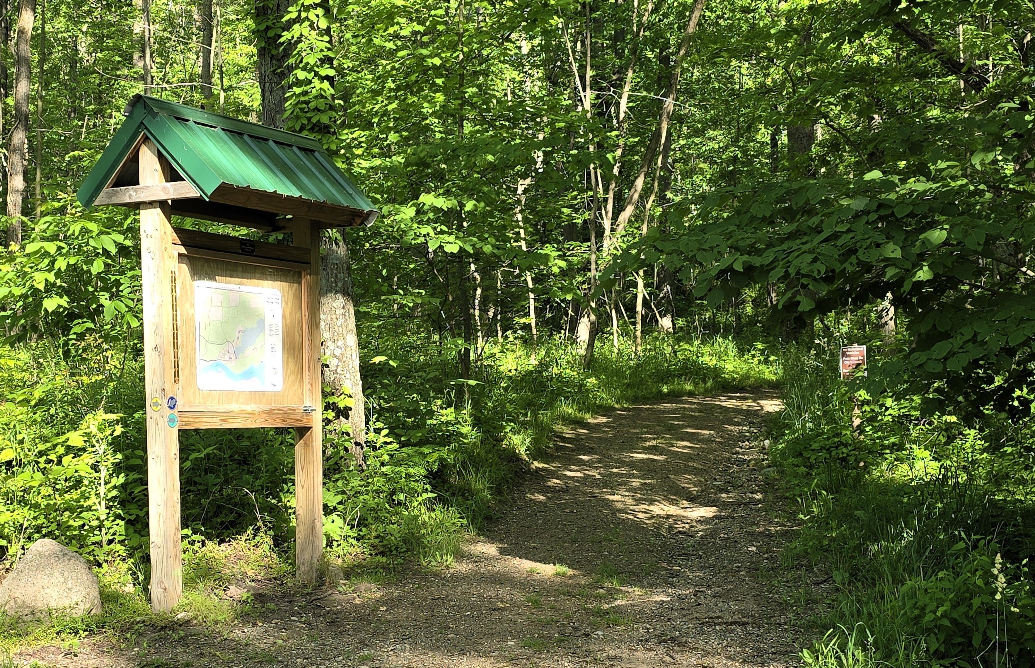 Trailhead with map and trail extending into distance. 