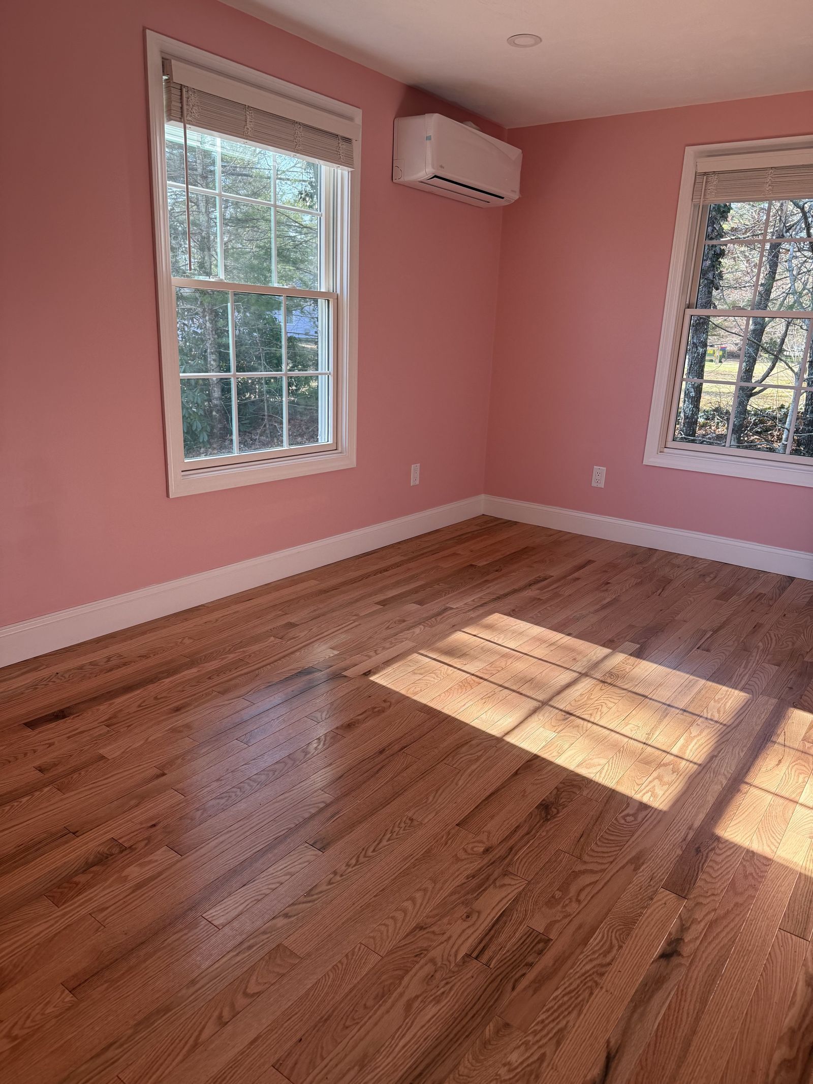 A photo of a bedroom painted pink with light colored hardwood floors