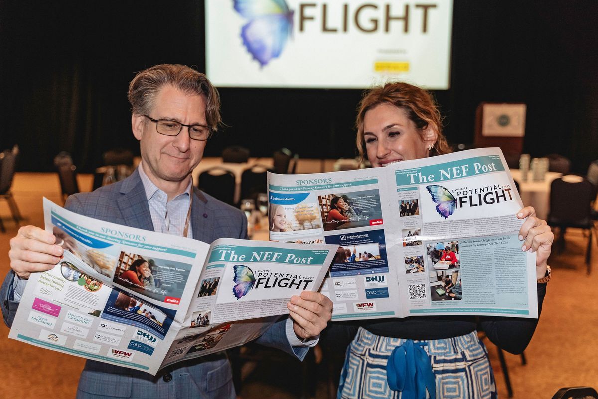 Attendees holding NEF newspapers