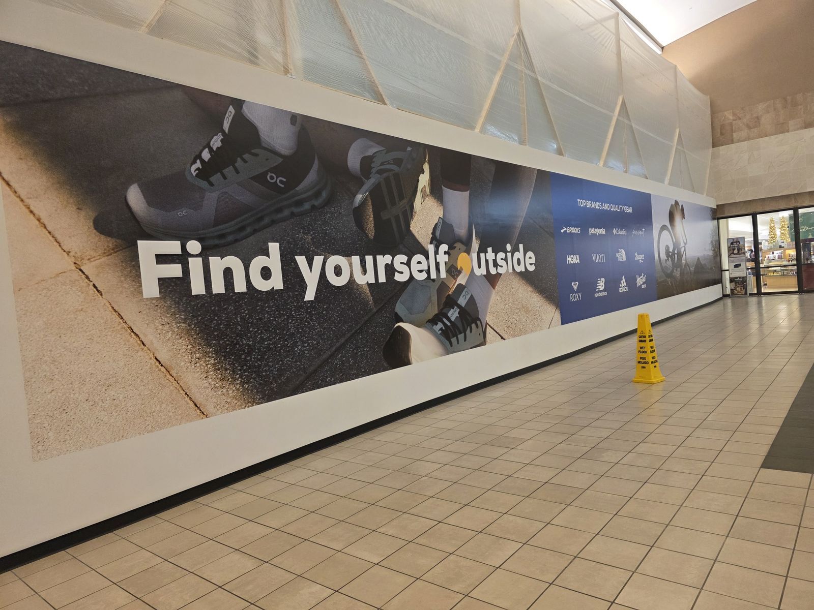 Large barricade wrap inside The Galleria mall displaying “Discover Delicious” with directional signage and vibrant food photography, promoting nearby restaurants like Chipotle, Potbelly, and Marble Slab.