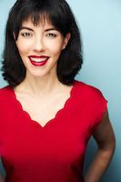 Alyssa H. Chase. A woman who is in her 30's. She is wearing a red dress and makeup. She is also smiling for the picture.