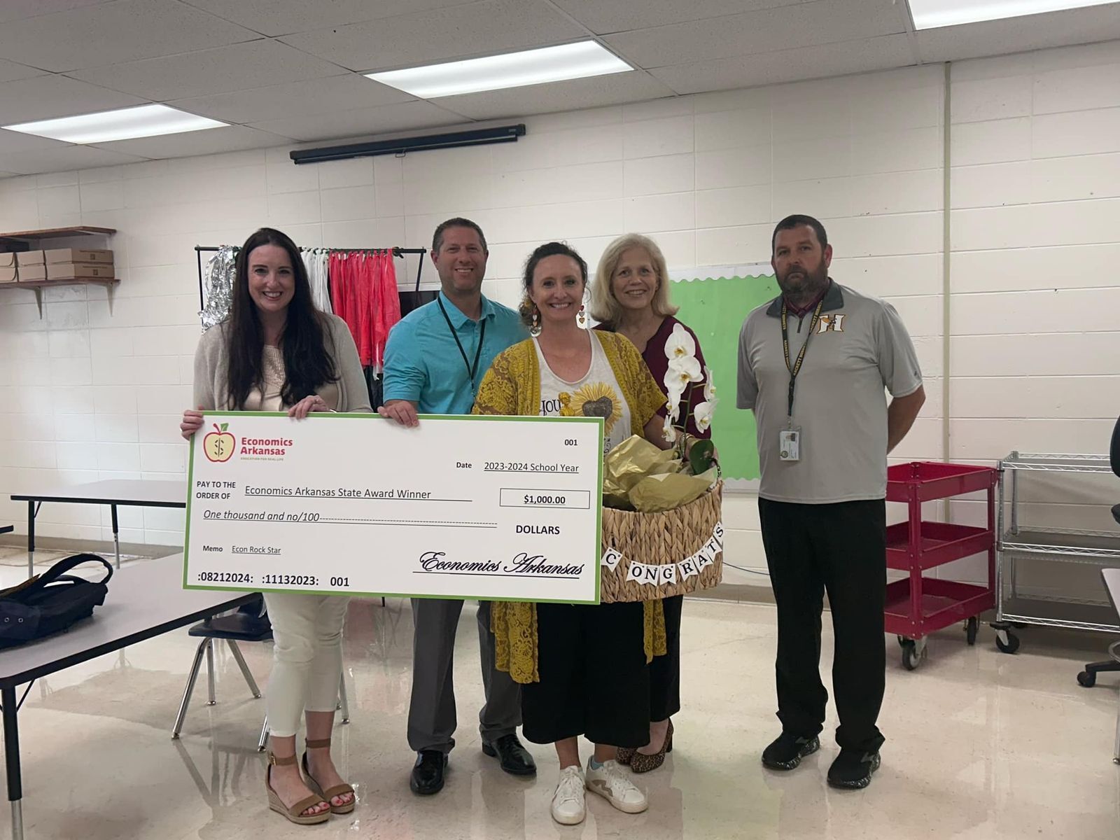 group of adults presenting large check and award to teacher