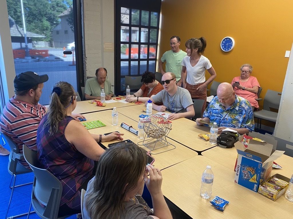 10 blind low vision group members sitting at table playing games and trying new technology devices