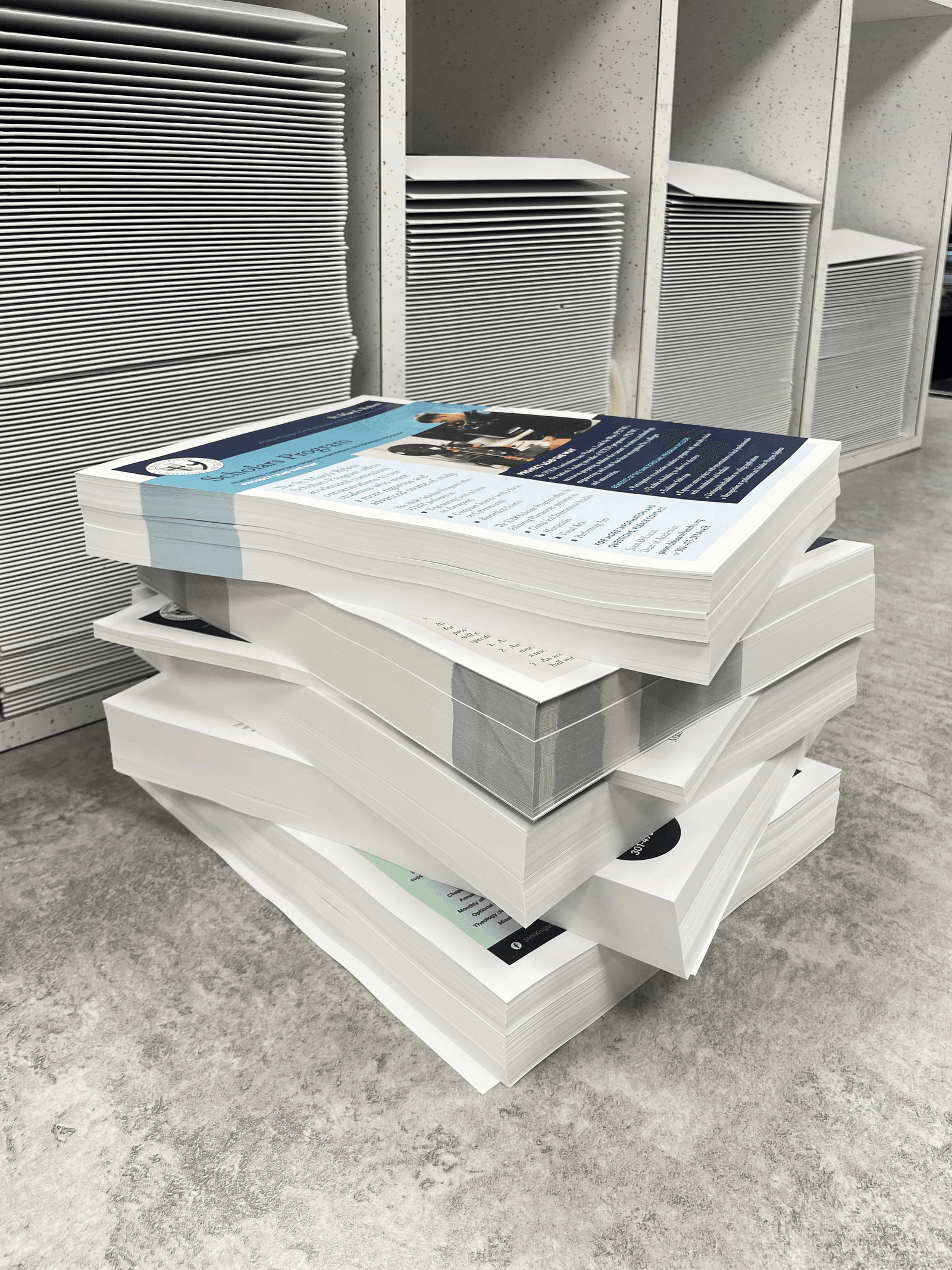 A stack of papers in front of shelves full of folded boxes.