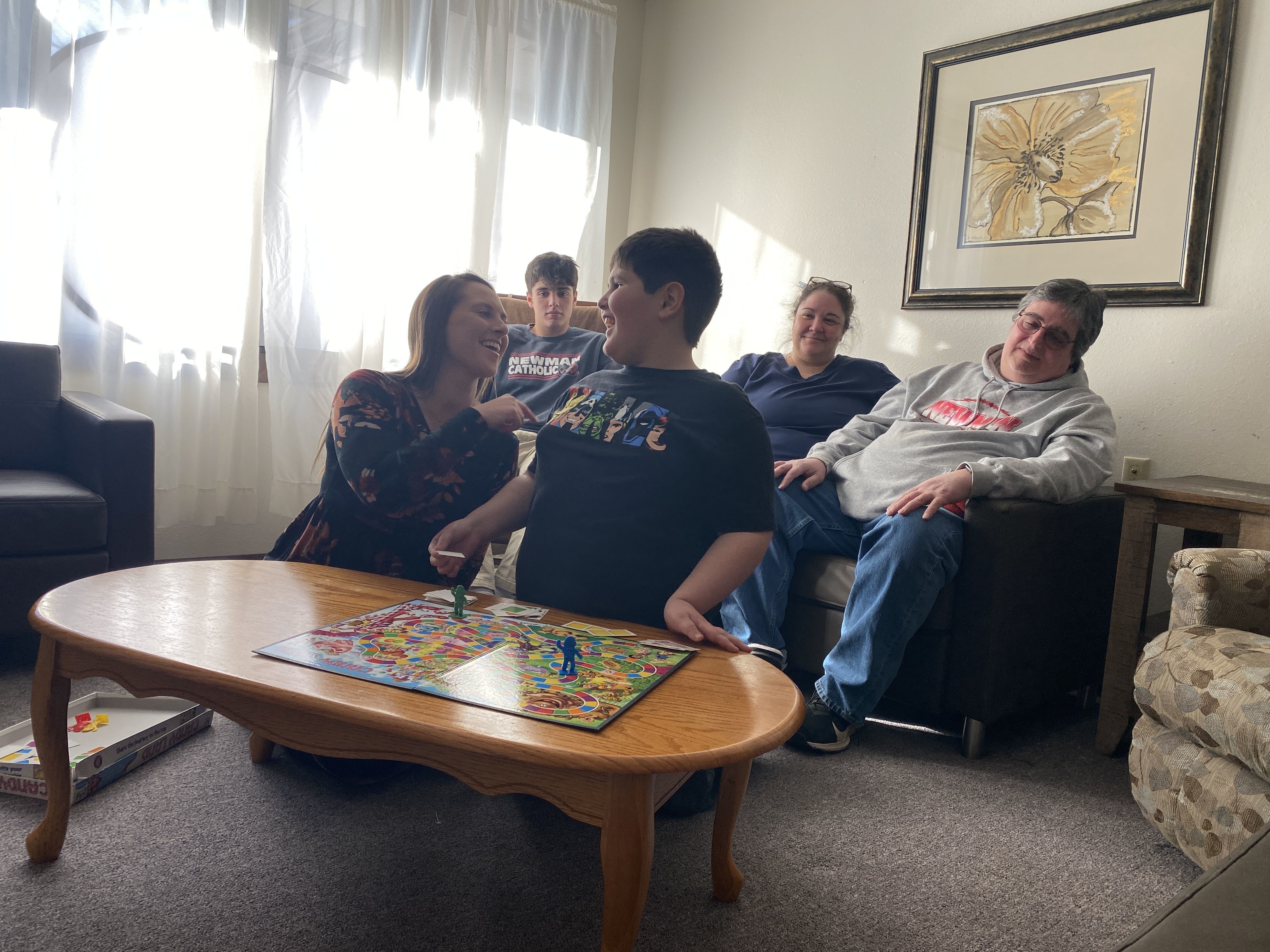 Sam plays Candyland with Laura Korth, CAC Clinic Director. The Joslins are seated behind the two.