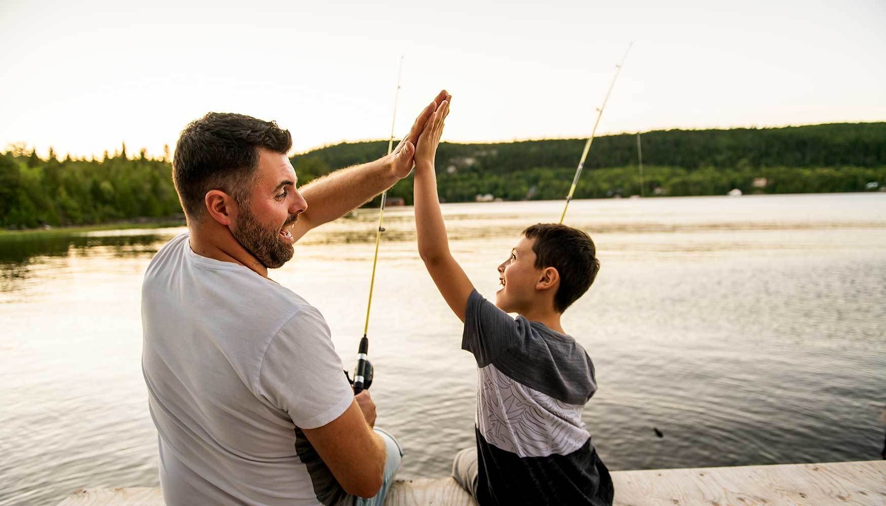 Boy and dad high fiving while fishing.