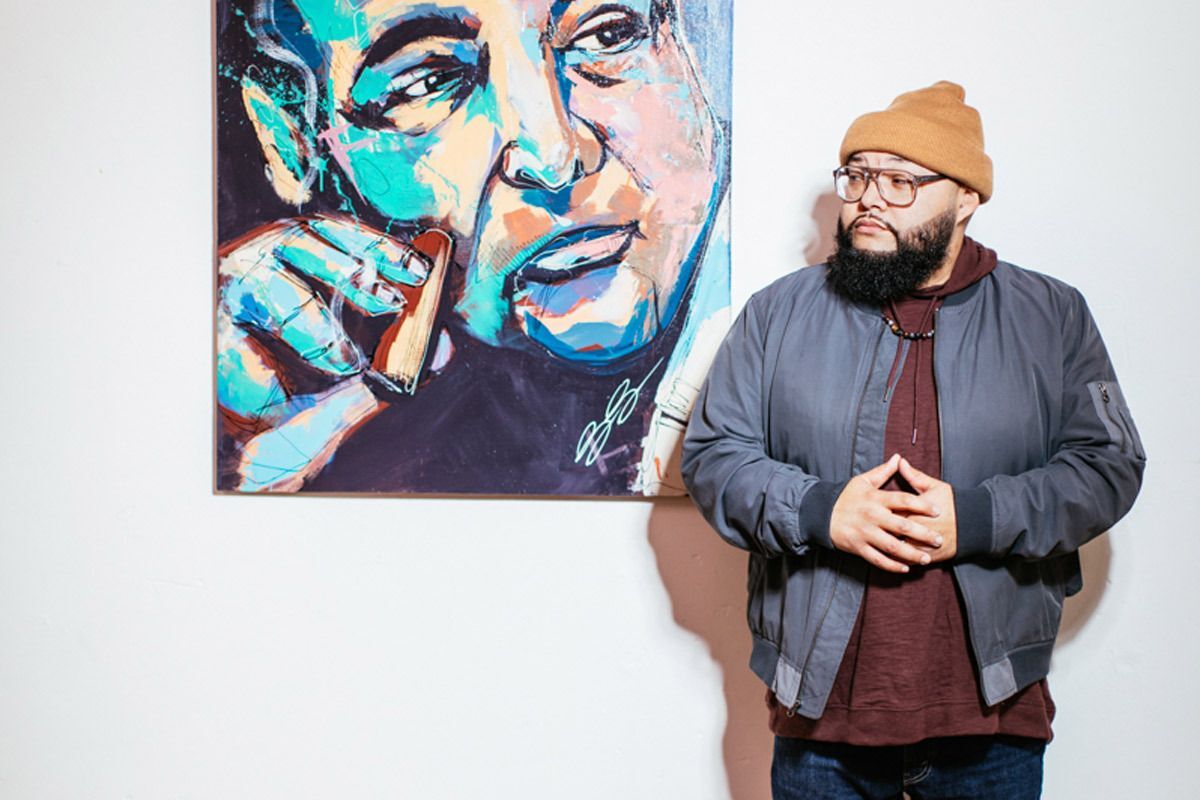 Omaha Artist Dany Reyes stands next to his painting.