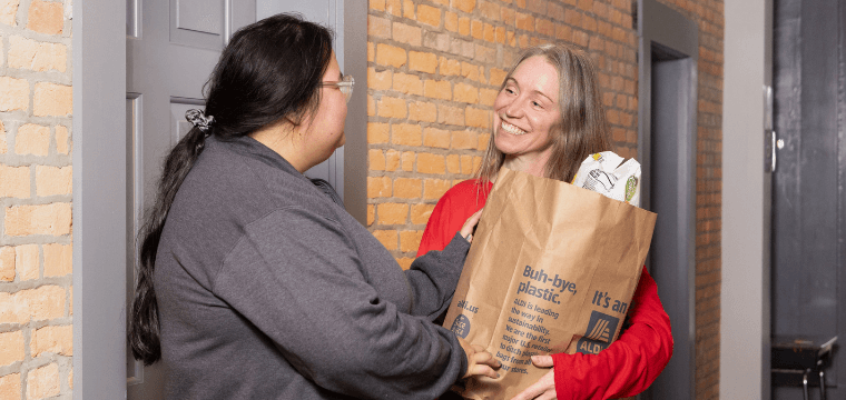 A case manager at Home for Families gives a client a bag of groceries as part of our material assistance programming