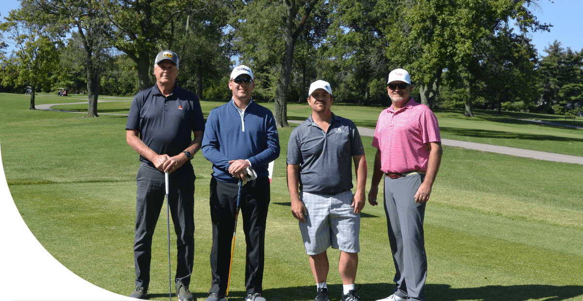 4 men standing with golf clubs on a golf course