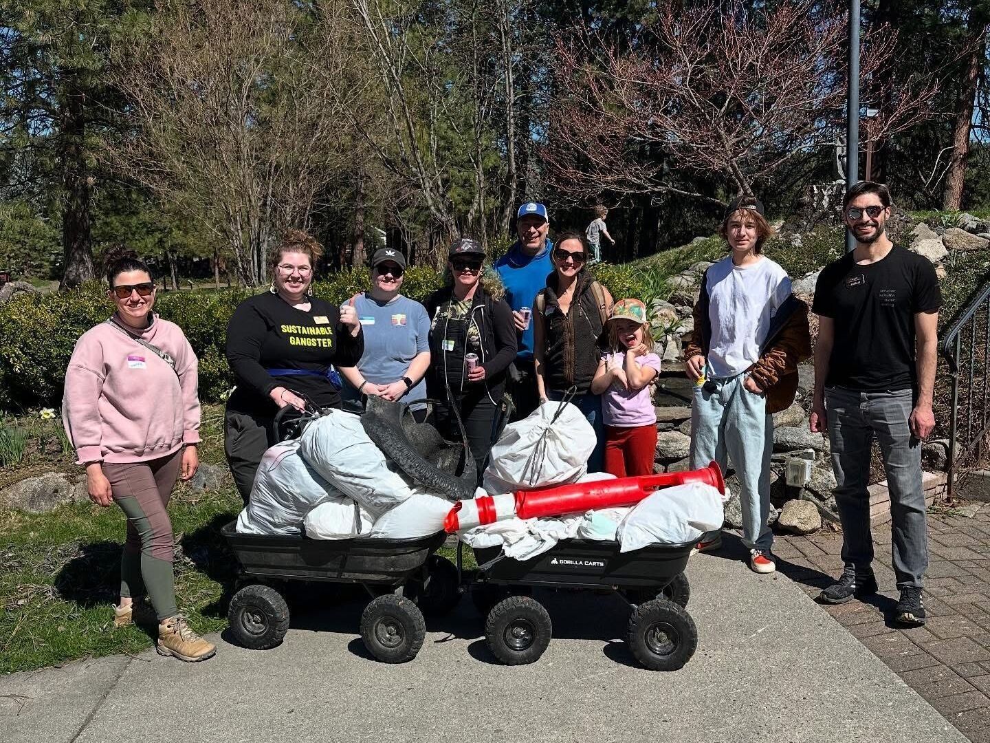 A group of staff and volunteers posing around the wagons of trash they picked up from the banks of the Wenatchee River.