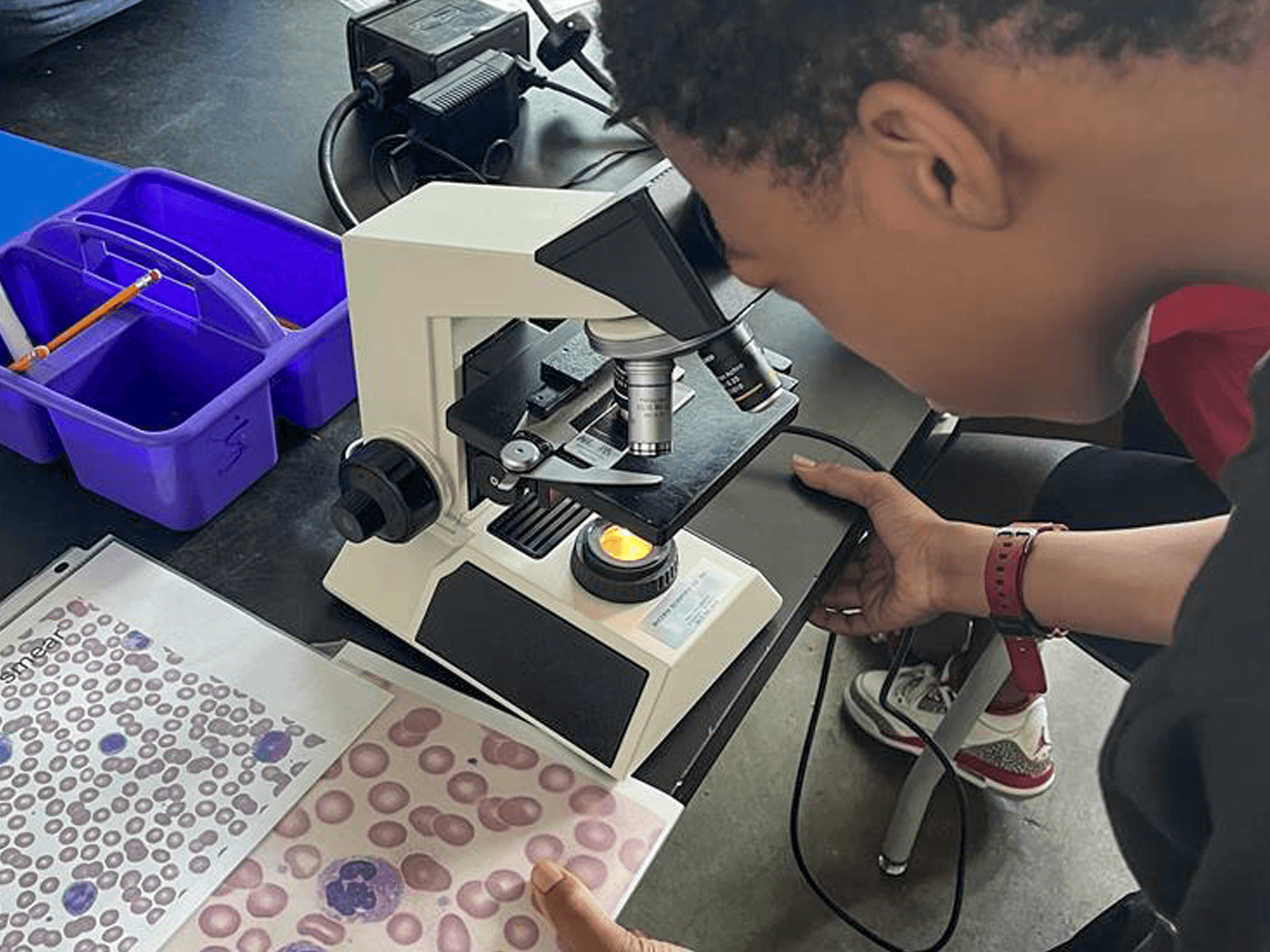 young person looking through microscope