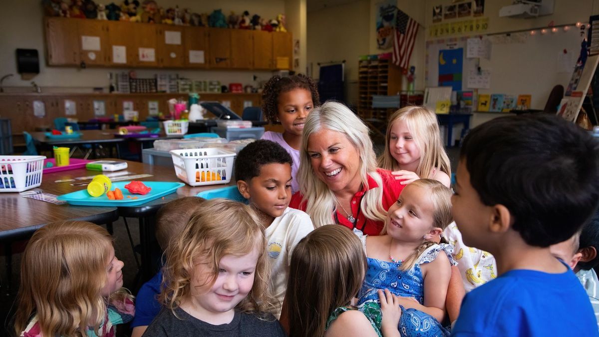 a class posing for a picture with their smiling teacher 