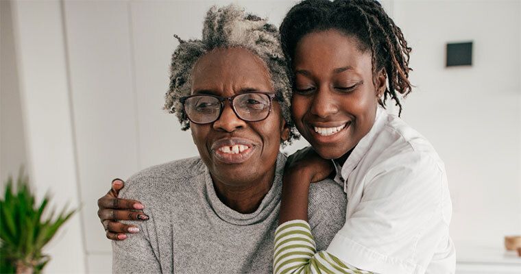 Image with two black women embracing and smiling.