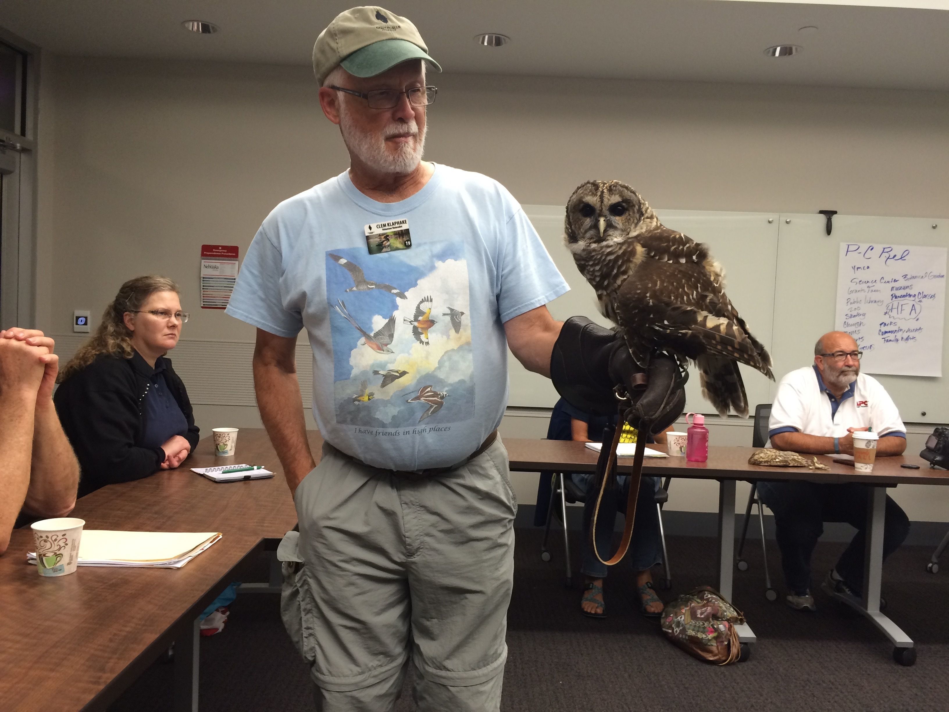 Image of a Barred Owl perched on the hand of Clem Klaphake within a classroom education setting.