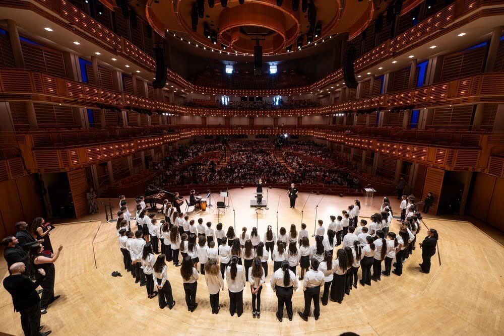 Seraphic Fire Youth Initiative students stand in an arc on the stage at the Adrienne Arsht Center, flanked by professional singers, and perform for an audience of over 1,500 peers.