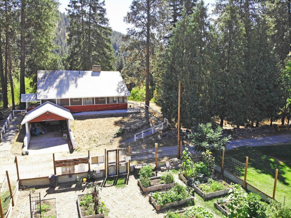 A red building with a garage and a garden bordering the home.