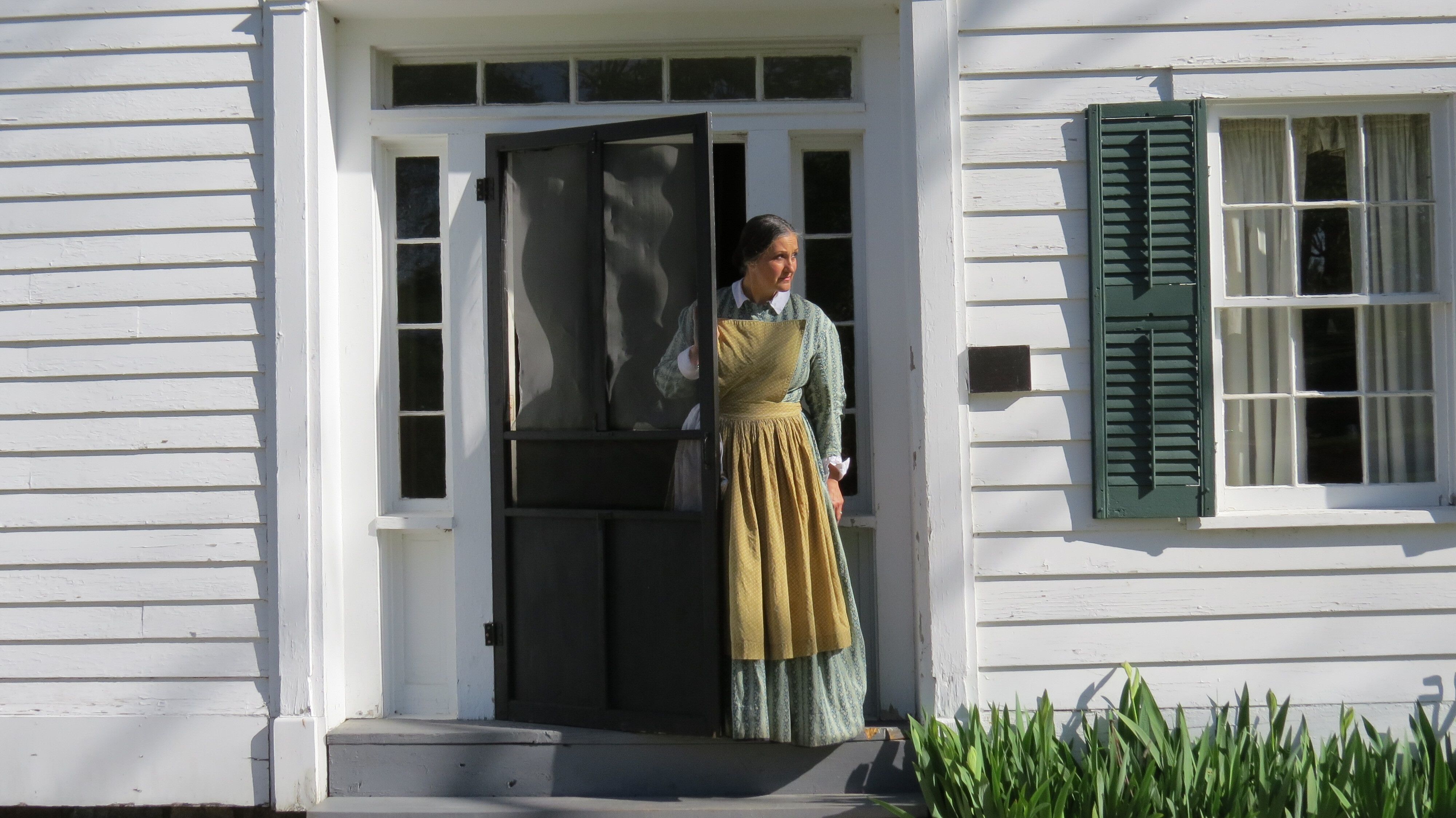 Costumed interpreter looks out the front door of the Bristol Inn. 