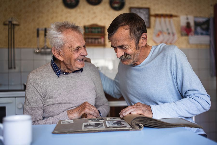 Caregiver adult son visits with his father smiling