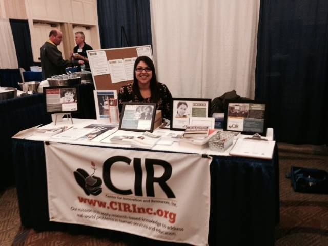 One of our team members sitting behind an informational booth at a conference.