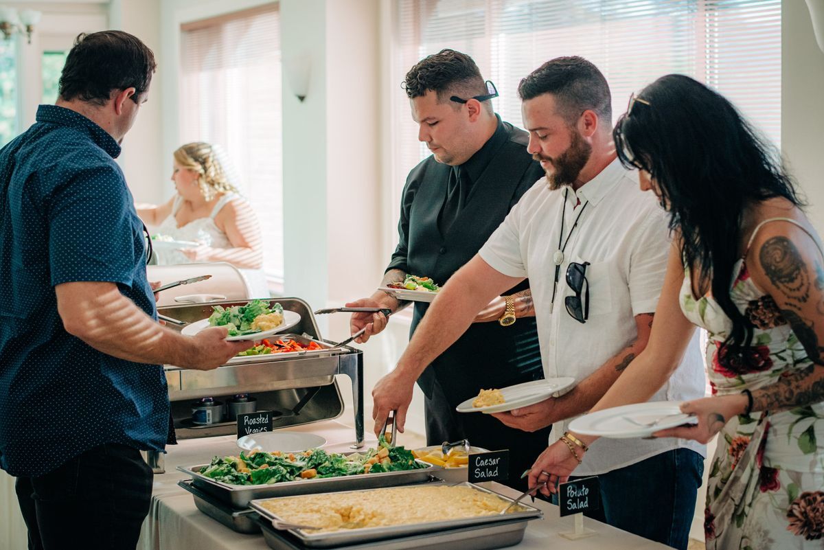 An image of a buffet line set up in the Sun Room with people serving food onto plates.