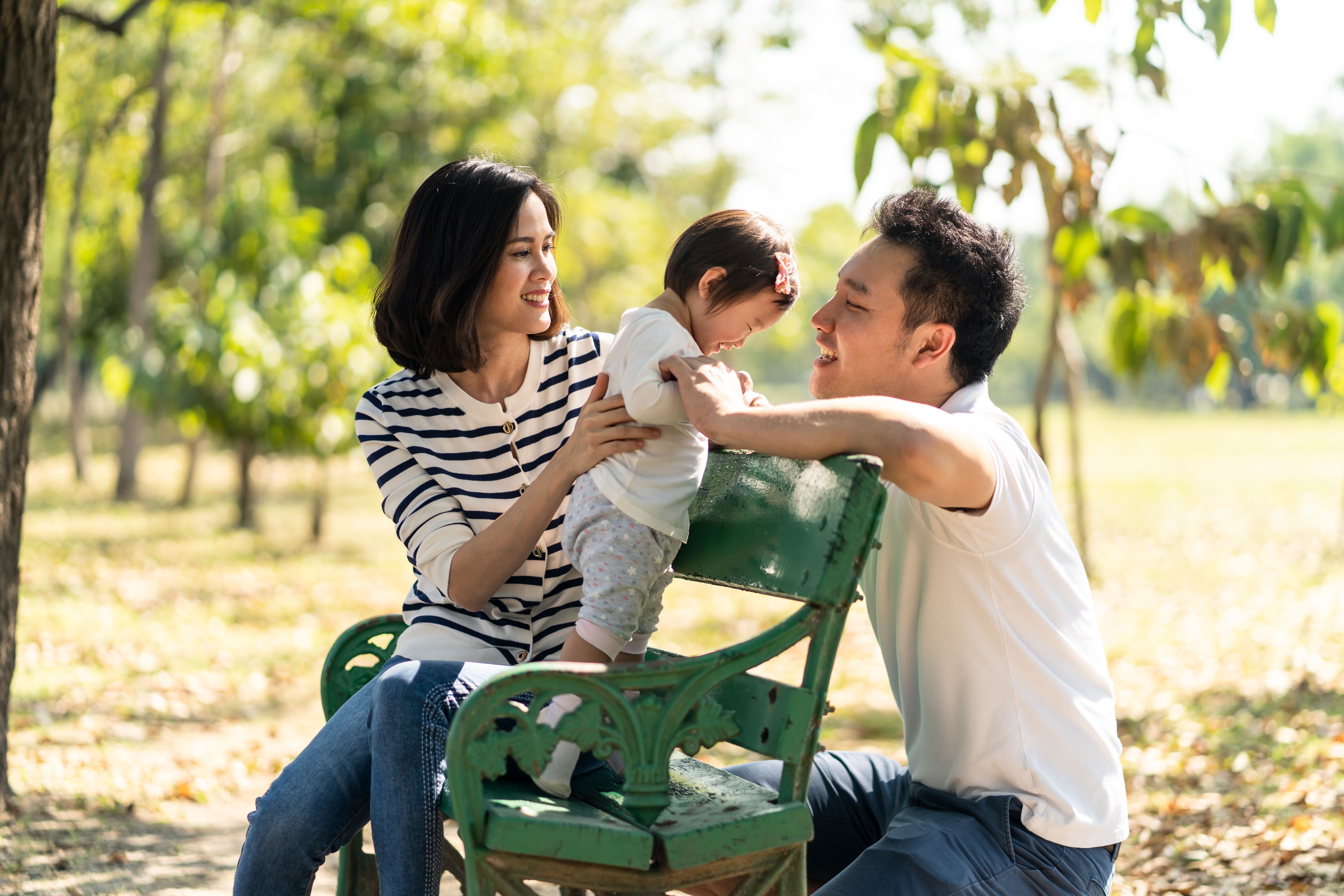 Photo of family enjoying sunshine on a park bench 