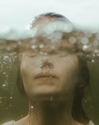 Photo of a woman with her face partially submerged in water.