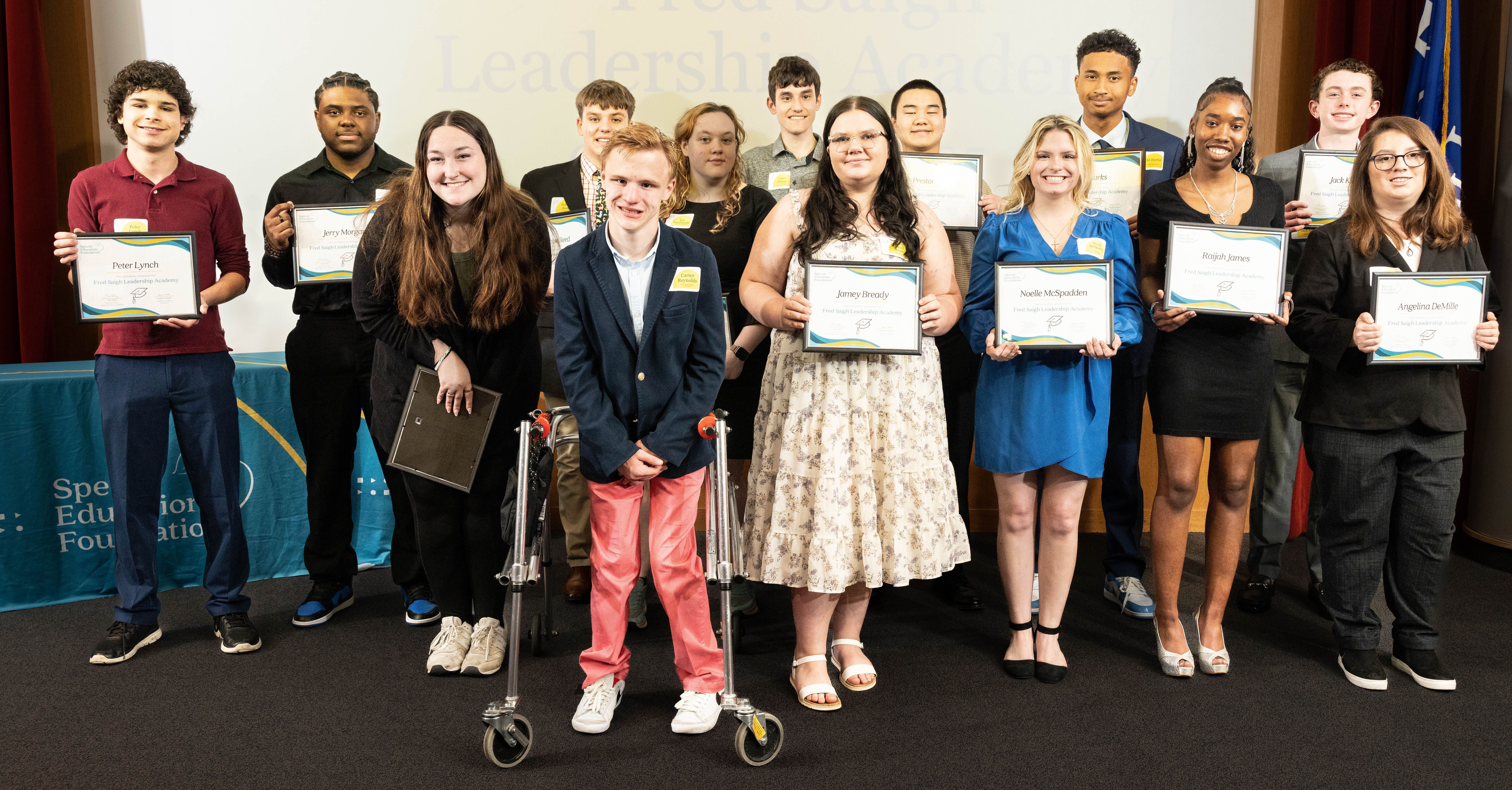 students on a stage holing up graduation certificates