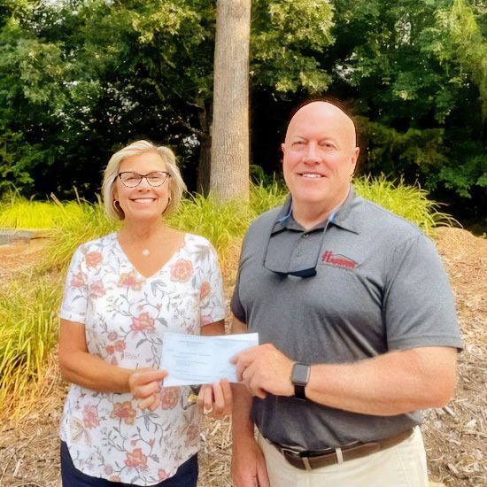Chris Moon, CEO of Harbin Lumber Company, presents PCHFH Executive Director Jill Evans with a donation check.