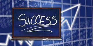 Chalkboard with the word 'SUCCESS' in white letters, overlaid on a blue graph with numbers and an upward arrow indicating growth.