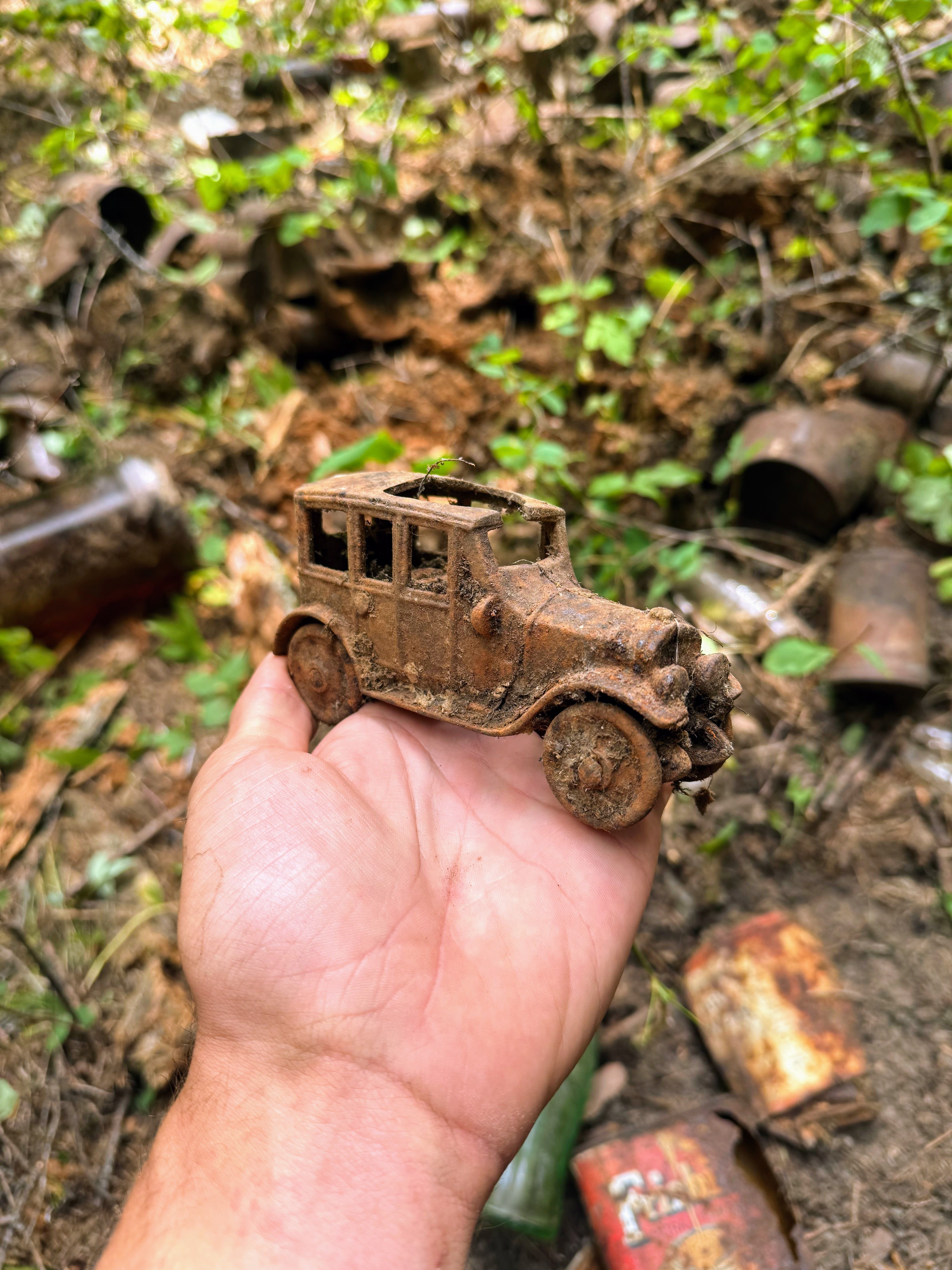 A rusty brown car being held in a hand.