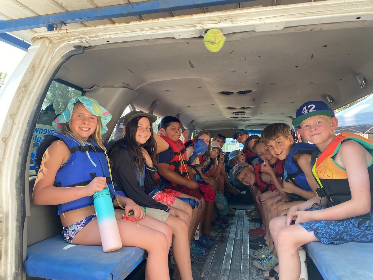 Kids in the back of a van being transported to a camp activity.