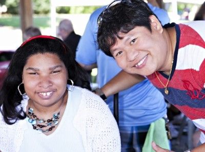 (Left) Woman in wheelchair smiling. (Right) PSRS employee leaning in and smiling