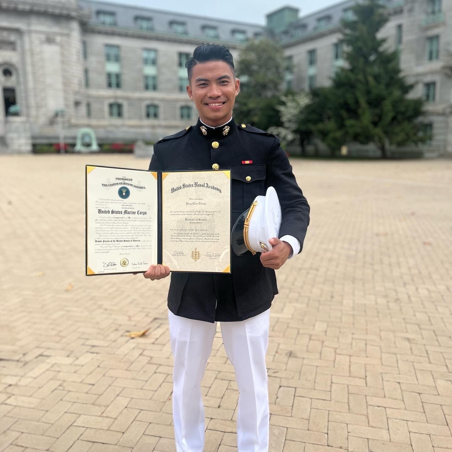 Peng Thang Smiling As He Holds Up His Naval Academy Graduate Certificate.