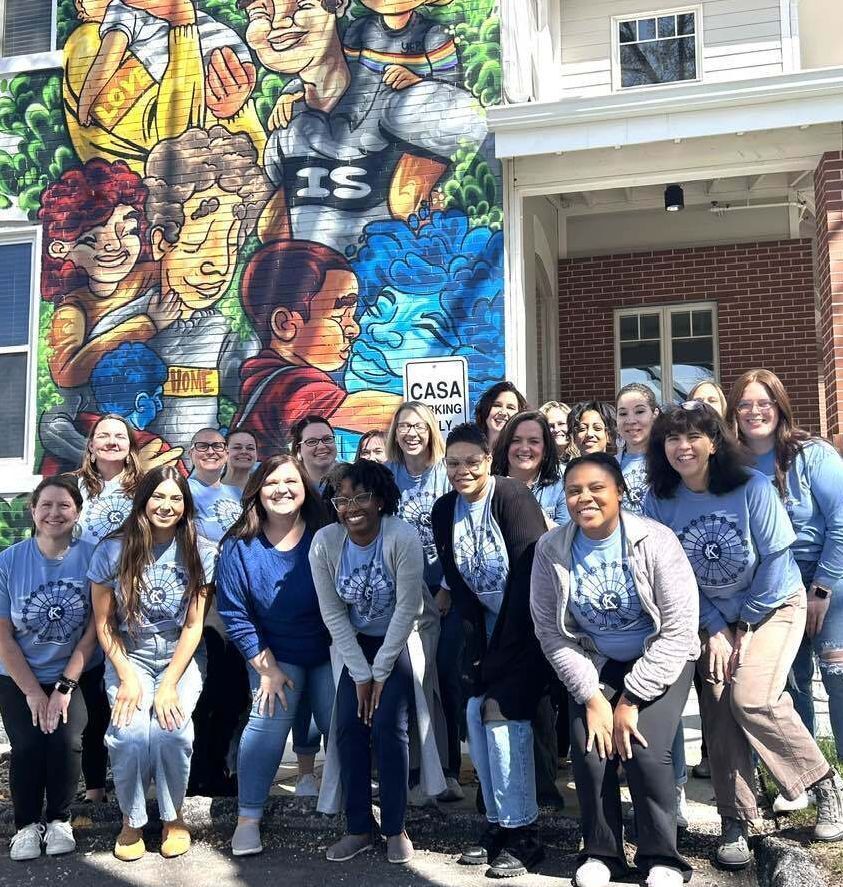 CASA Staff members wearing blue t-shirts in front of the CASA house outdoor mural