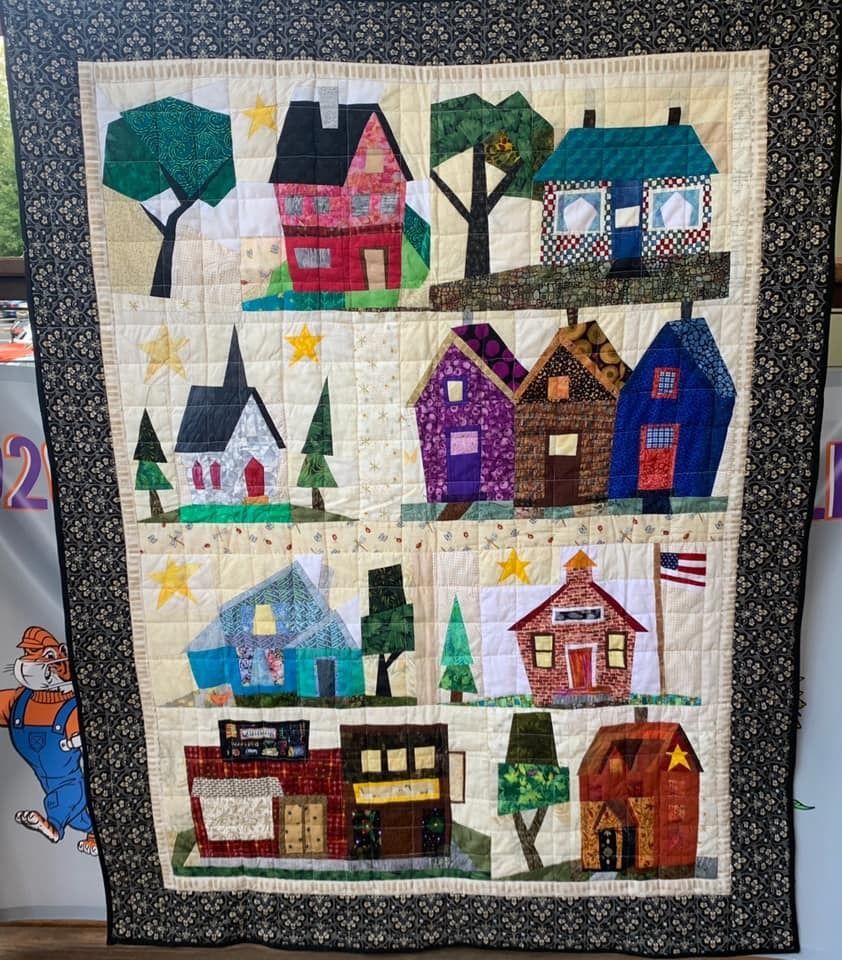 A multicolored quilt displaying different houses.