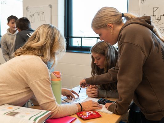 Teacher helping students with math problems.