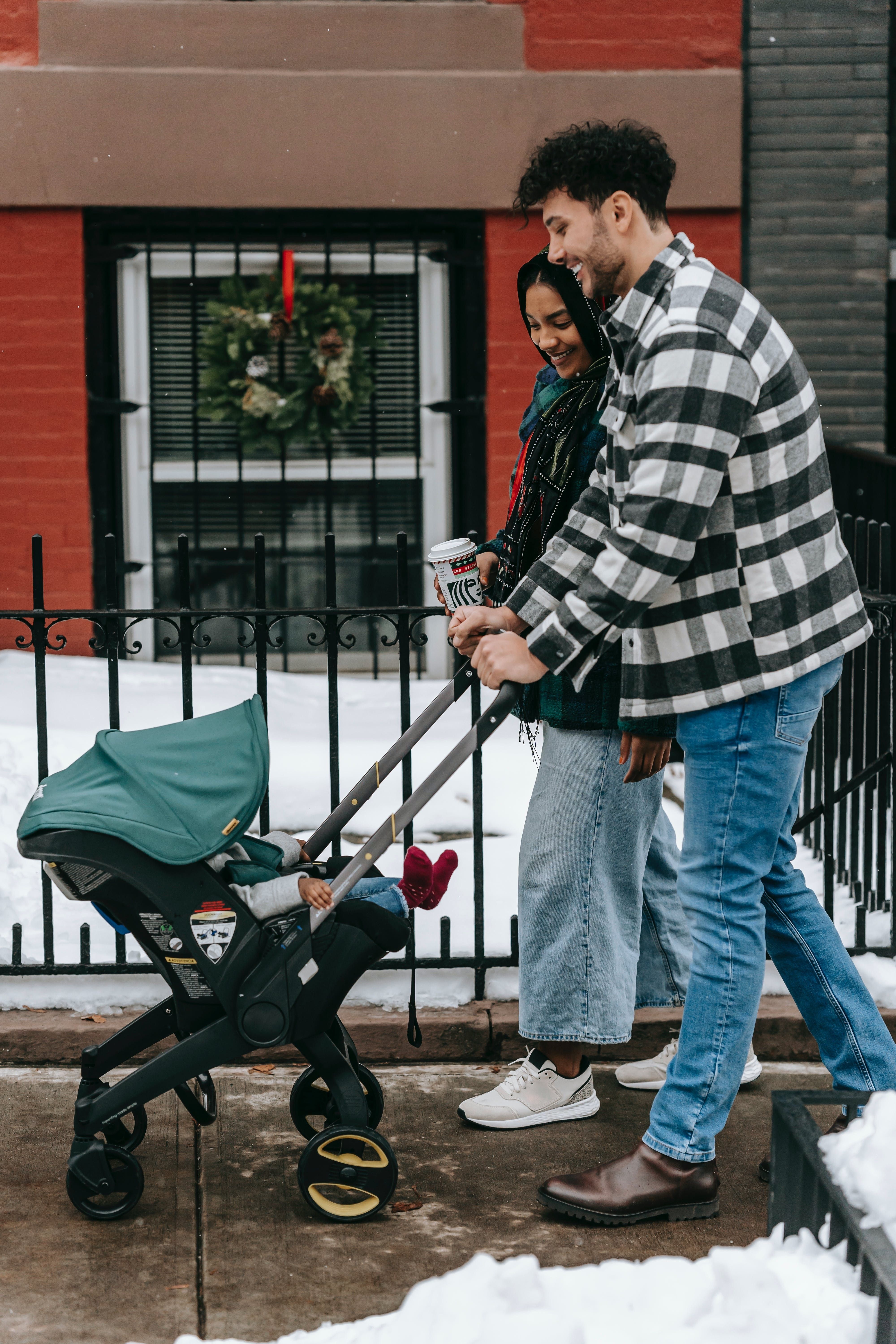 Couple walking with baby in stroller outside apartment.