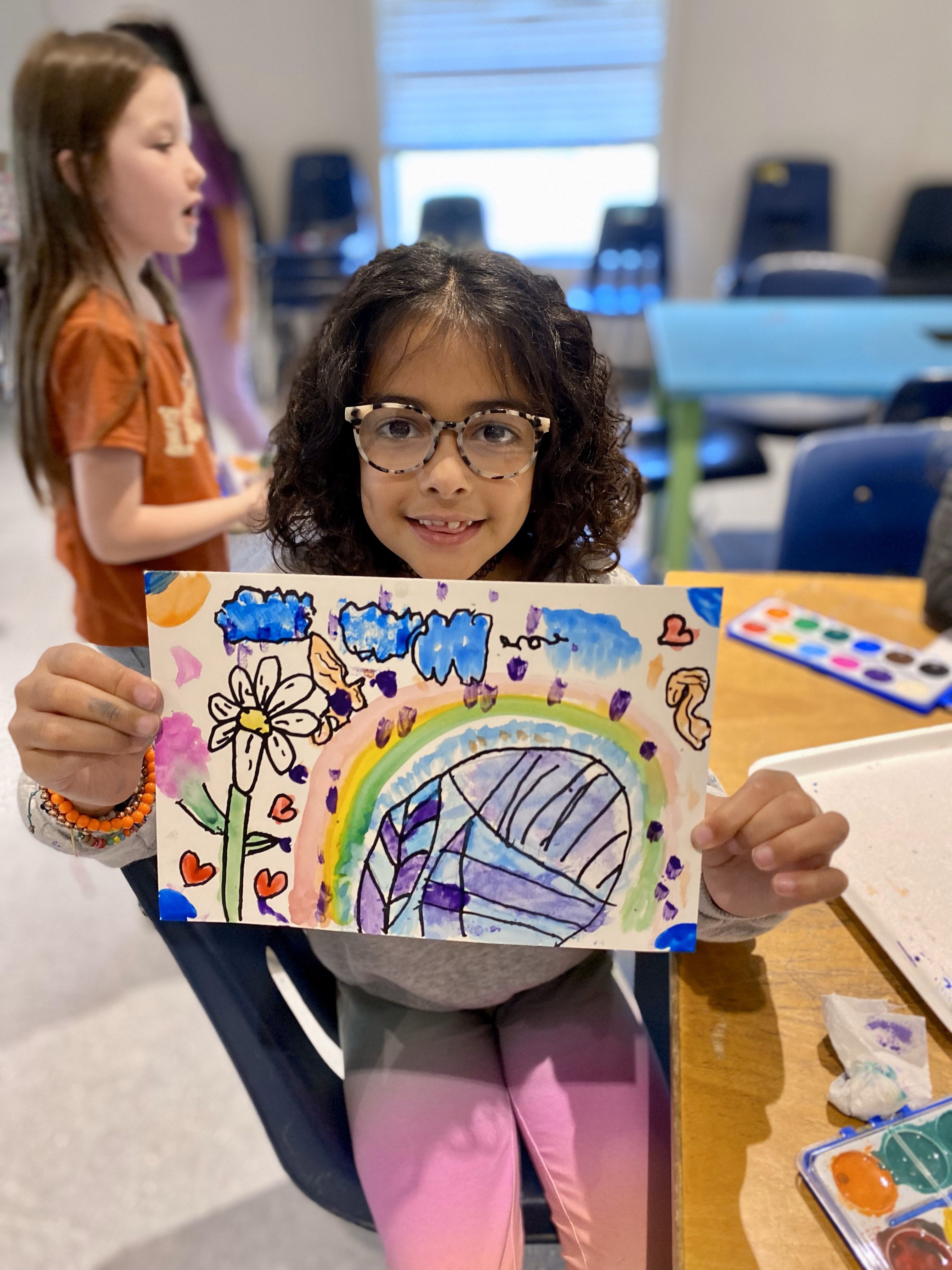 A happy student shows off artwork from a Sunshine & Smiles kit