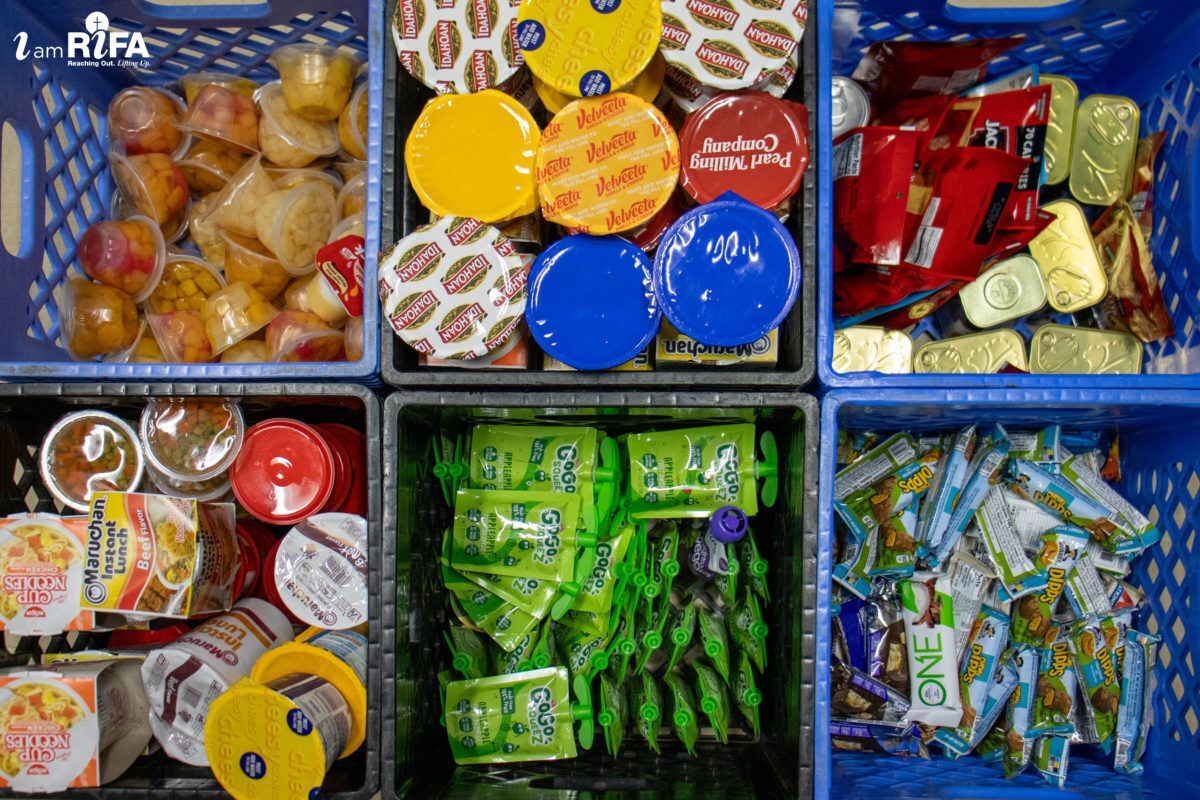 Assorted packaged food items in six baskets, including fruit cups, snack packs, noodle cups, squeeze pouches, and wrapped bars.