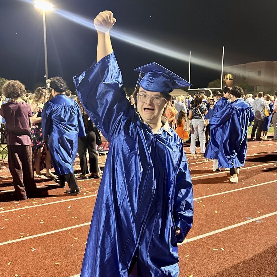 Student on graduation day with hand raised in the air in celebration